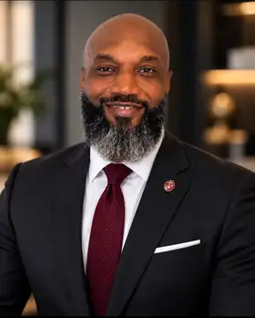 Portrait of Javice Chisholm, Founder & CEO of Mansa Global Services, wearing a dark suit with a Marine Corps lapel pin