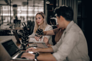 Group of young professionals collaborating at a desk with robotic equipment in a modern tech office.
