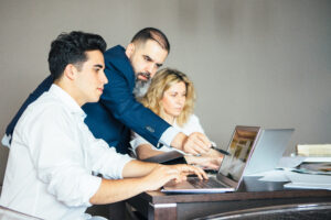 Business team gathered around a laptop discussing a project with their manager pointing at the screen.