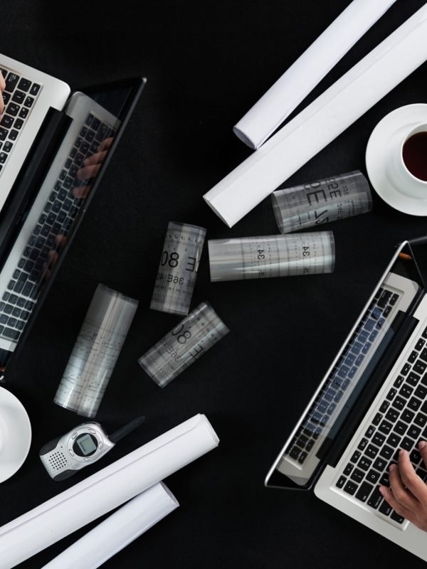 Close-up of rolled blueprints and a laptop on a desk.