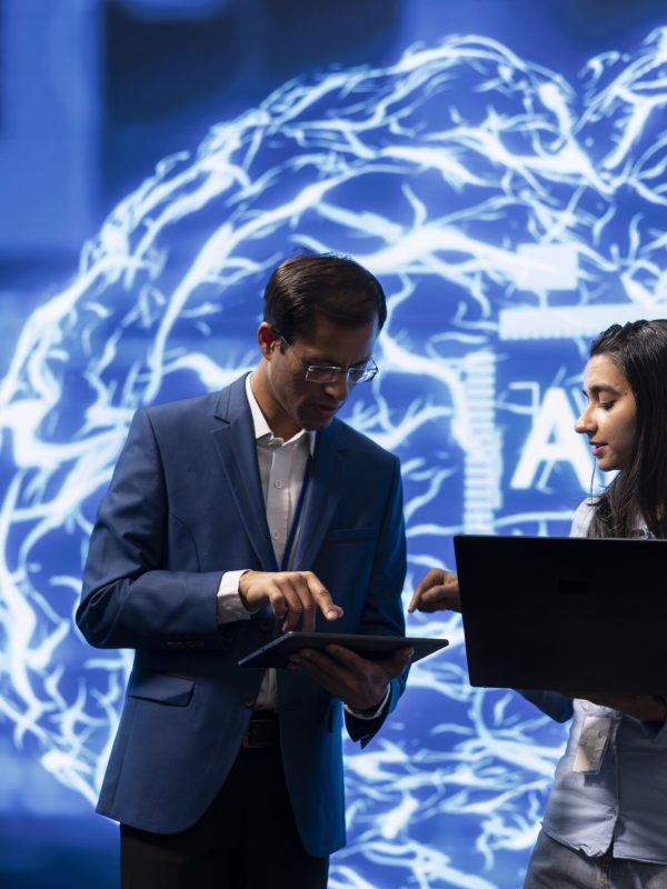 Two software engineers use neural networks modeled after human brain to solve complex problems. IT experts in high tech workspace using artificial intelligence to look at data